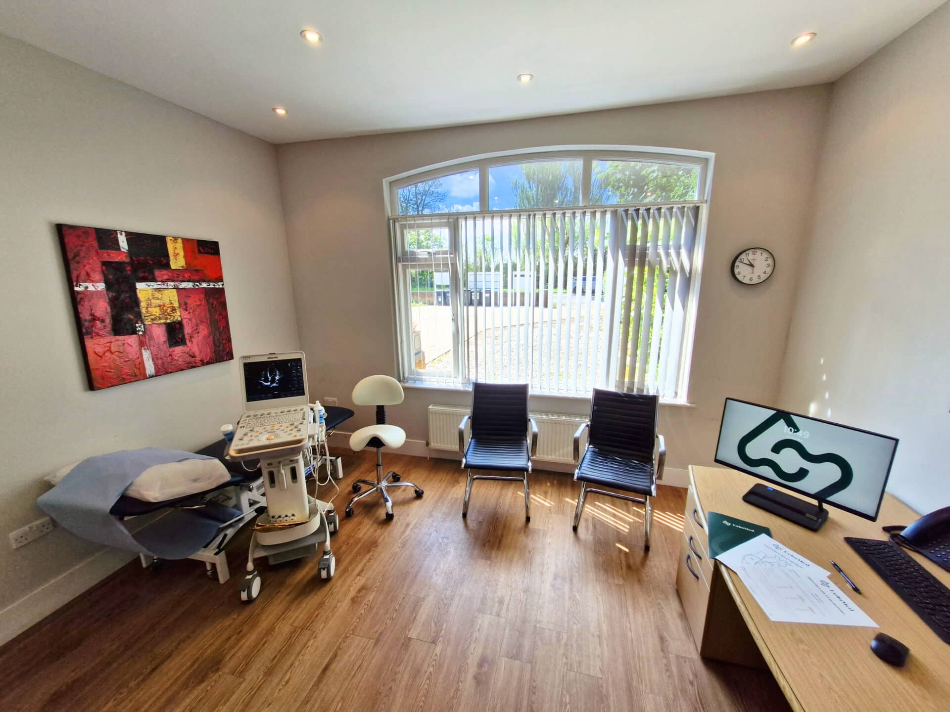 EchoMed clinic with a desk, computer, chairs, and an echocardiogram ultrasound machine.
