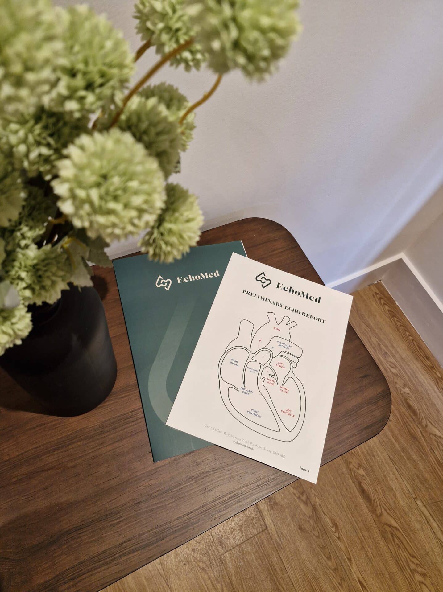 A table with flowers in a vase and two EchoMed booklets on it.