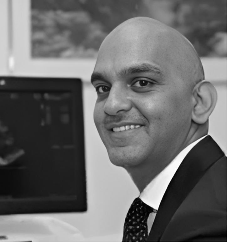 A man sat at a desk, smiling.